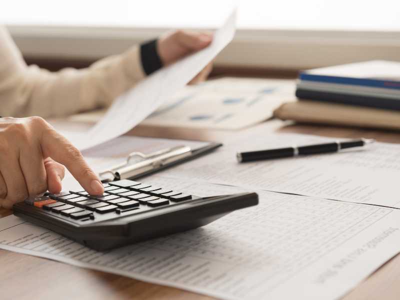 A person using a calculator with papers in hand. federal window replacement program