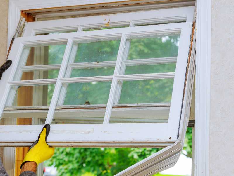 When to replace windows. A cracked window with peeling paint and condensation inside, surrounded by drafts and visible damage to the frame. 